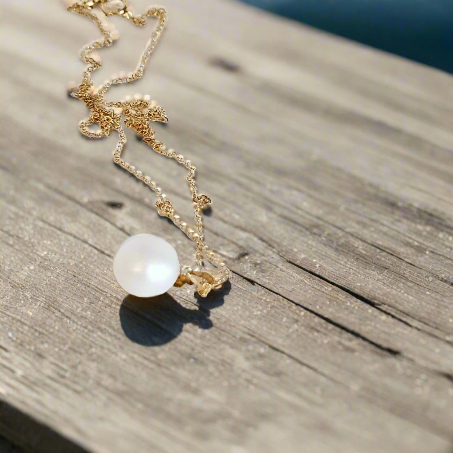 Pearl necklace with gold chain laying on a wooden table